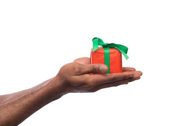 Hombre negro sosteniendo una caja de regalo en manos aisladas sobre fondo blanco. Presente, vacaciones, concepto de felicitaciones