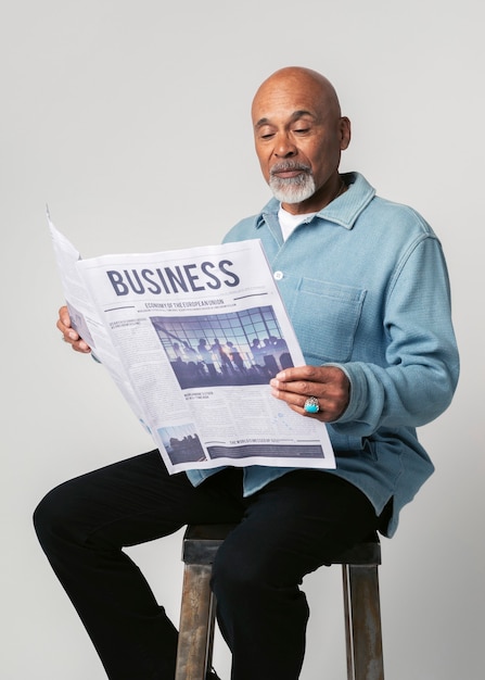 Hombre negro en un taburete leyendo un periódico