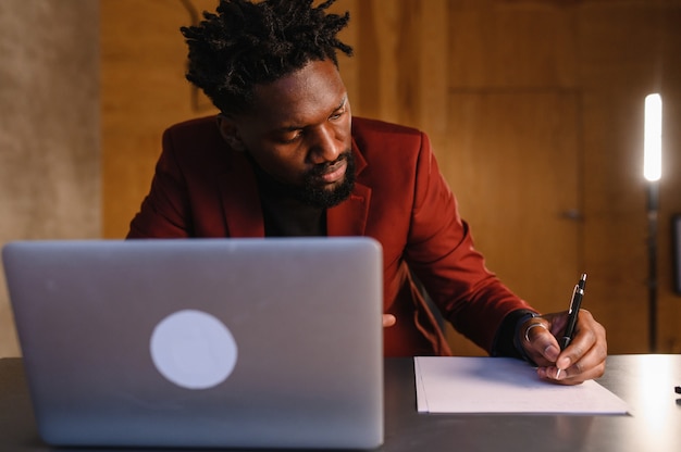 Un hombre negro trabaja en una computadora portátil primer plano de su cara video conferencias