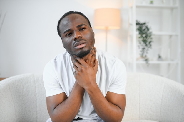 Hombre negro triste que sufre de dolor de garganta tocando el cuello resaltado espacio de copia