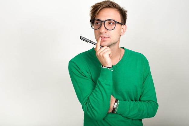 Hombre nerd con cabello rubio contra la pared blanca