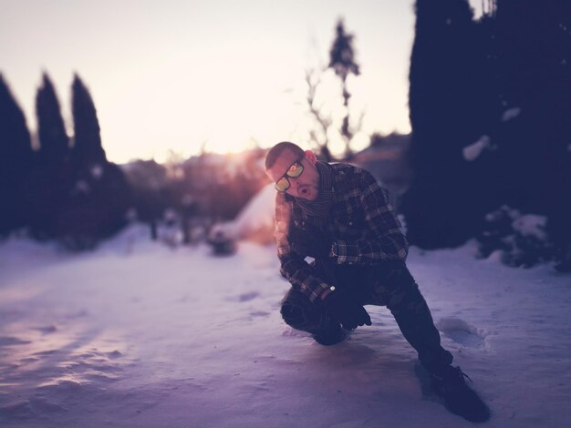 Foto hombre en la nieve durante la puesta del sol