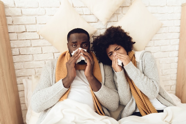 Foto hombre y niña en la cama sonarse la nariz.