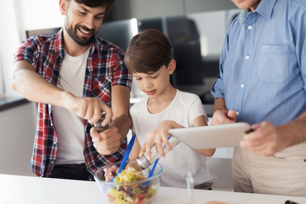 Un hombre, un niño y un anciano preparan una ensalada.