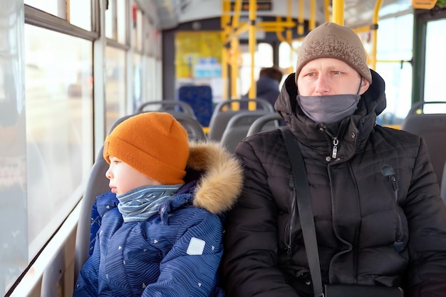 Un hombre y un niño en un autobús que llevan máscaras médicas padre e hijo en un bus de transporte público durante covid