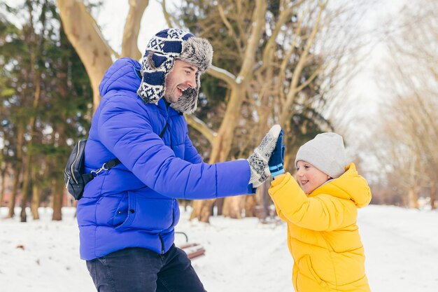 Un hombre y un niño disfrutan de la nieve en el parque en invierno, padre e hijo se divierten juntos