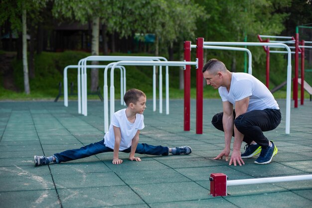 Un hombre y un niño haciendo ejercicios de estiramiento en un parque infantil.