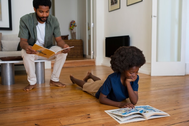 Foto hombre y niño de tiro completo leyendo cómics en casa