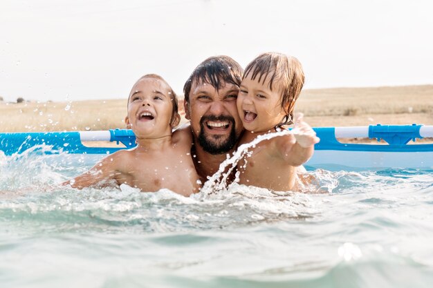 Un hombre con niños nadando en la piscina, papá con hija en el agua.