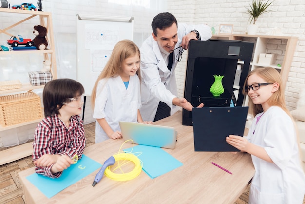 Foto el hombre y los niños se sorprenden de cómo funciona la impresora 3d.