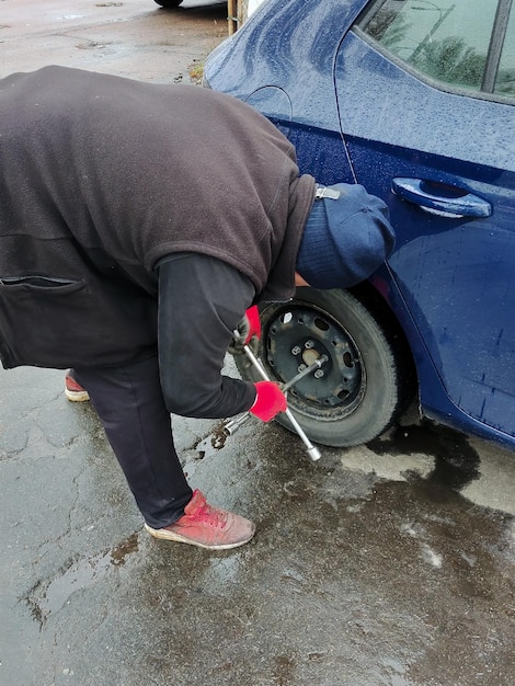 Un hombre no identificado con apariencia de delincuente roba la rueda trasera de un coche desenroscándola