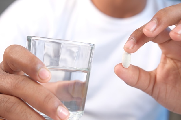 Hombre no reconocido con camisa blanca tomando medicina