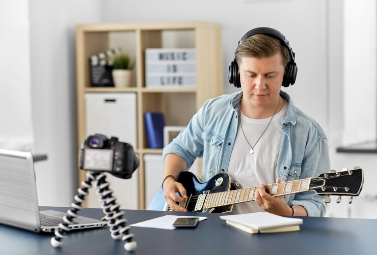Foto hombre o blogger con cámara tocando la guitarra en casa