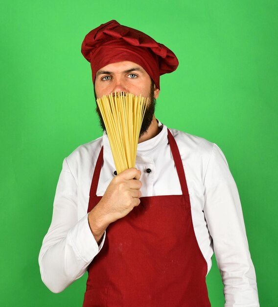 Foto hombre o hipster con barba sostiene macarrones sobre fondo verde