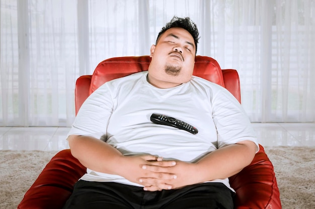 Hombre obeso asiático tomando una siesta en el sofá