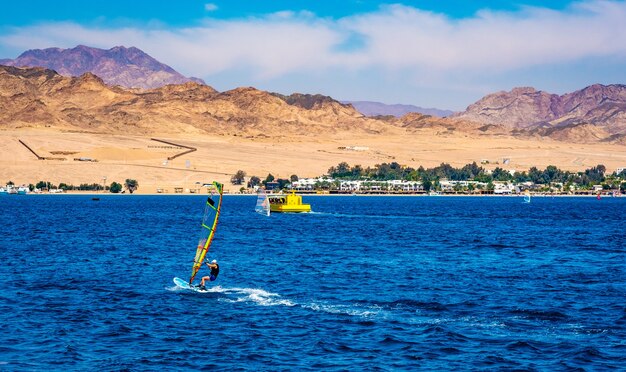 Hombre de ocio con deporte extremo de windsurf en mar azul