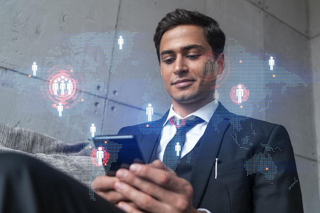 Foto hombre en la oficina trabajando con smartphone buscando nuevos países para trabajar con holograma de mapa mundial internacional escribiendo teléfono doble exposición