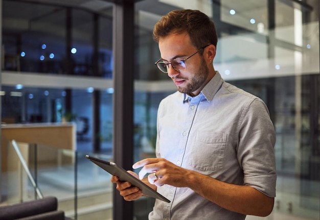 Hombre en la oficina trabajando en una tableta por la noche en la oficina y probando la estrategia de campaña para la empresa de marketing Empleado profesional dedicado que trabaja hasta tarde en el proyecto y usa tecnología en el negocio