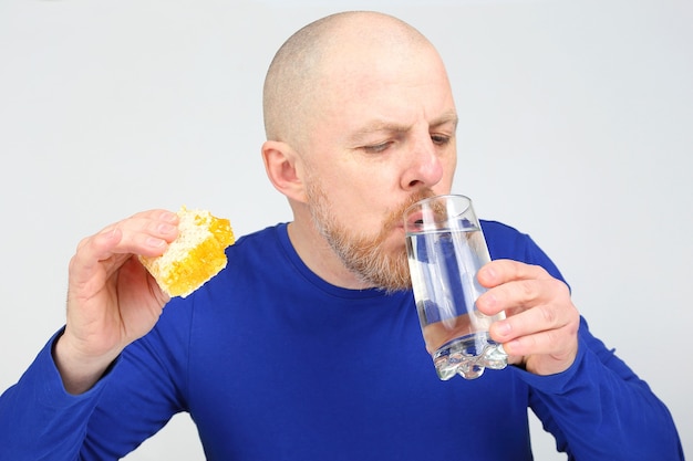 El hombre ofrece comer miel de abeja y un vaso de agua. Dieta saludable