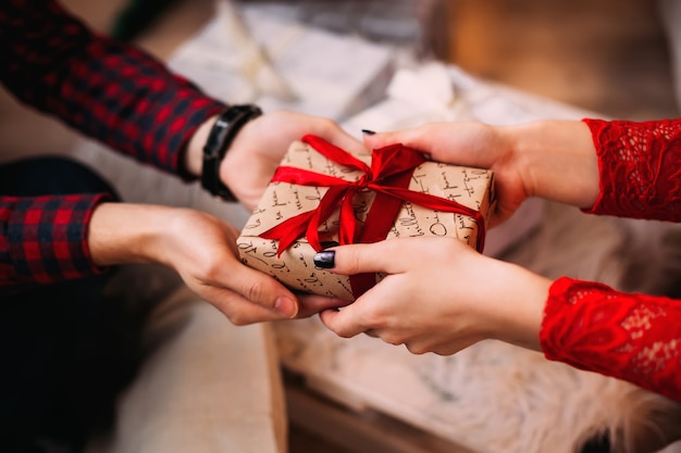 Hombre ofreciendo un regalo a su novia y haciéndola muy feliz.