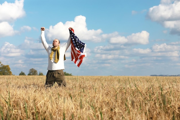 Hombre ondeando la bandera americana de pie en el campo agrícola de granja de hierba, vacaciones, patriotismo, orgullo, libertad, partidos políticos, inmigrante
