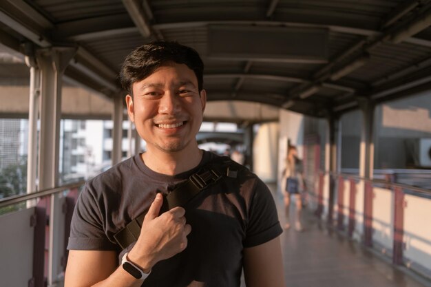 Hombre ordinario feliz caminando en la plataforma del tren aéreo en Bangkok