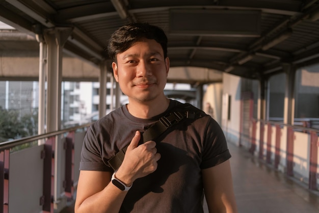 Hombre ordinario feliz caminando en la plataforma del tren aéreo en Bangkok