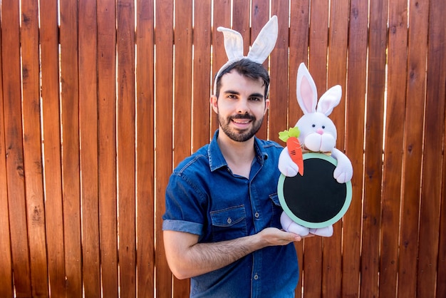 Hombre con oreja de conejo de pascua sosteniendo conejito de pascua y huevos de pascua