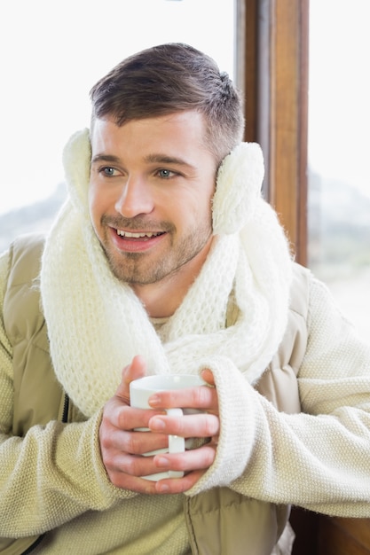 Hombre con orejera con taza de café contra la ventana