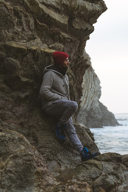 Un hombre en la orilla rocosa mirando al mar sobre unas rocas.