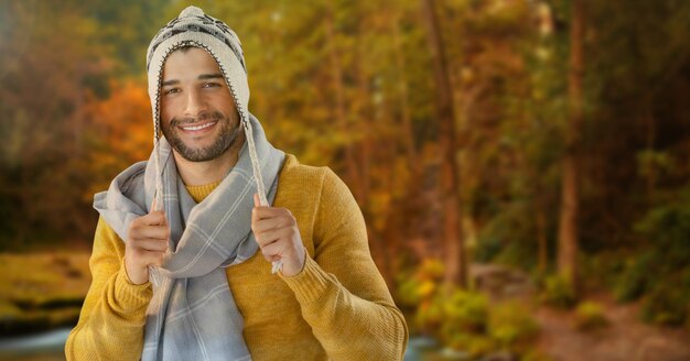 Hombre en otoño con bufanda y gorro en el bosque