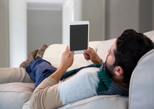 Hombre en otoño con tableta en el sofá en casa