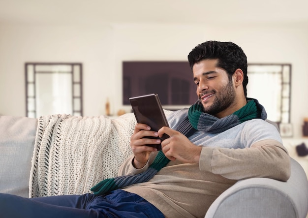 Hombre en otoño con tableta en el sofá en casa