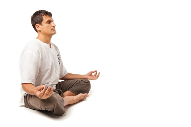 Hombre pacífico haciendo yoga y meditando, aislado sobre un fondo blanco.