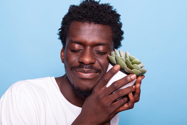 Hombre pacífico sosteniendo una maceta pequeña con planta y sonriendo