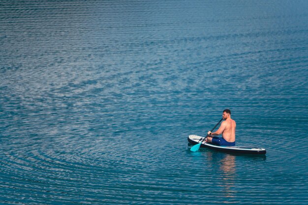 hombre en paddleboard en el medio del lago