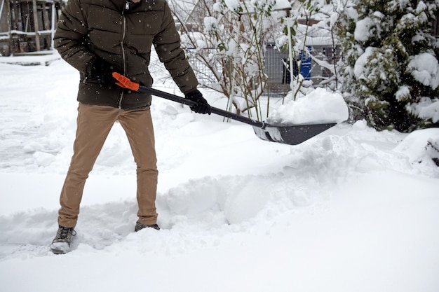 Hombre con pala de nieve limpia aceras en vista lateral de invierno