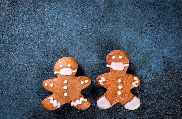 Hombre de pan de jengibre en mascarilla. Hombre de pan de jengibre en máscara médica. Quédate en casa, concepto de coronavirus. Navidad pandémica. Pareja de galletas en máscara. Año nuevo covid 19.