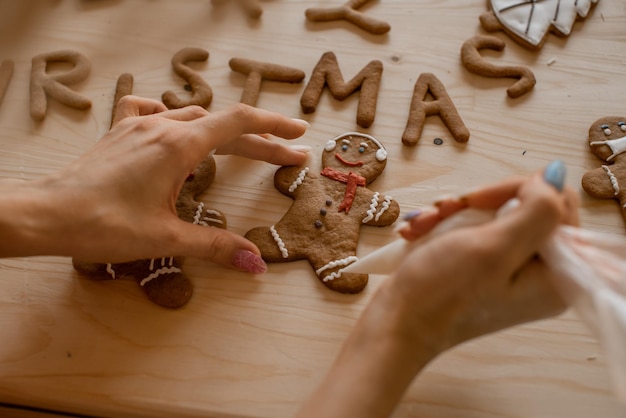 Hombre de pan de jengibre en proceso Mujer cocinando en mesa de madera Inscripción de hornear una feliz Navidad