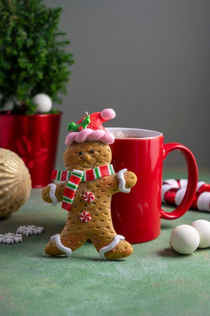 Hombre de pan de jengibre y taza roja con bebida de chocolate caliente y adornos de invierno Fondo abstracto de Navidad