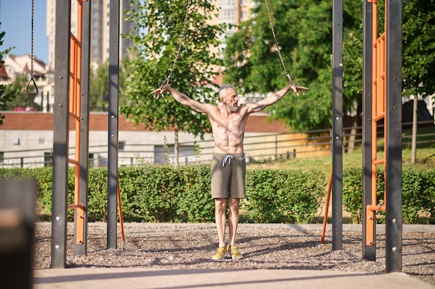 Un hombre en pantalones cortos haciendo ejercicio en un campo de deportes en el parque