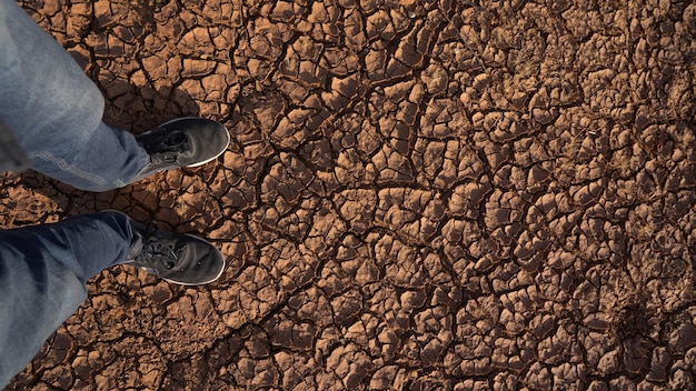 Foto un hombre parado en el fondo seco y agrietado en la parte superior ve los efectos del calentamiento global