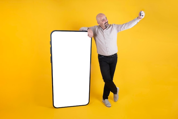 Un hombre parado junto a un iphone gigante con una pantalla en blanco