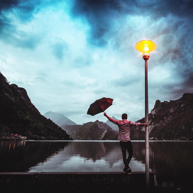 Foto hombre con paraguas de pie en el lago contra el cielo