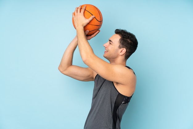 Hombre en pared azul aislado jugando baloncesto