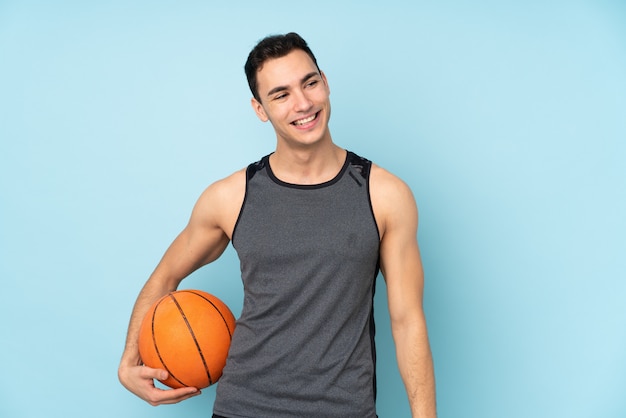 Hombre en pared azul aislado jugando baloncesto