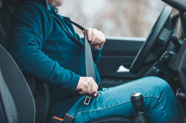 Hombre de pasajero abrocharse el cinturón de seguridad en el coche, el transporte y el concepto de seguridad