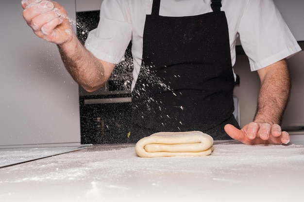 Hombre pastelero cocinando croissants caseros preparando el hojaldre y agregando trabajo de harina en casa