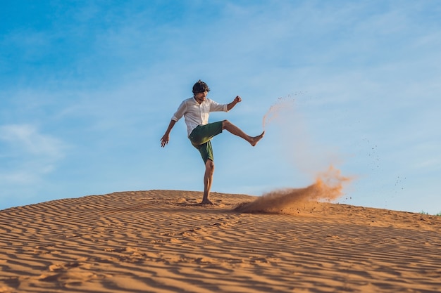 Hombre pateando arena en un desierto rojo salpicaduras de concepto de ira