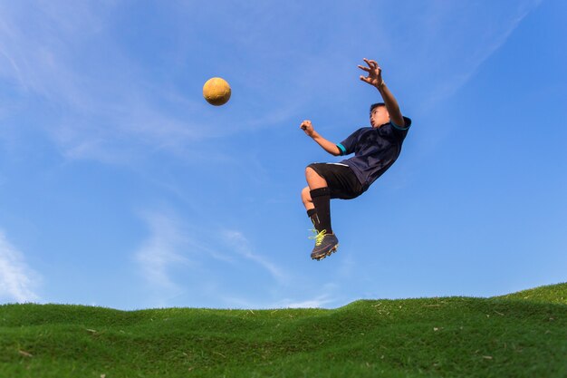 hombre patear la pelota en el estadio con cielo azul